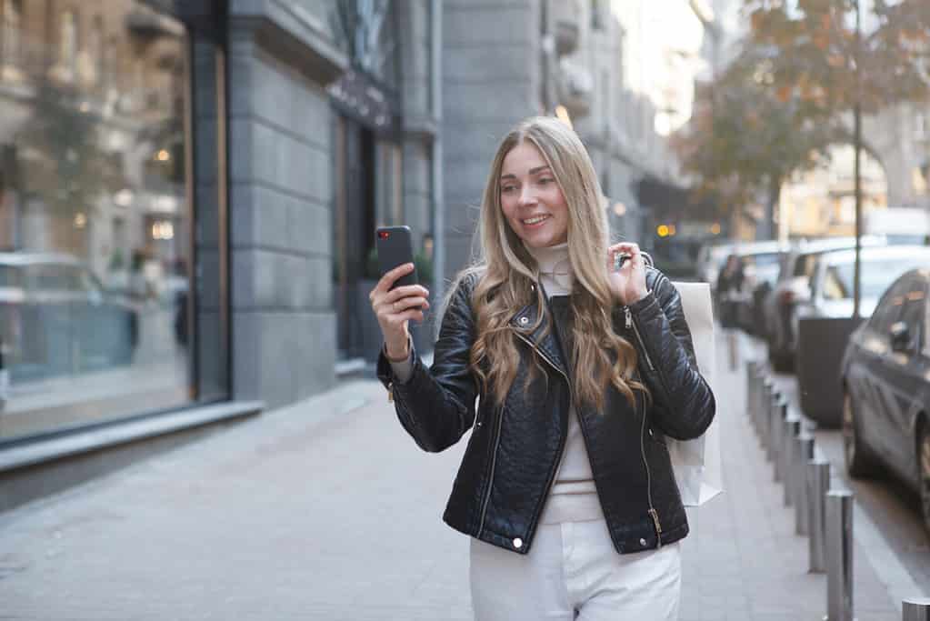 Lovely cheerful woman taking selfie outdoors, while shopping in city center