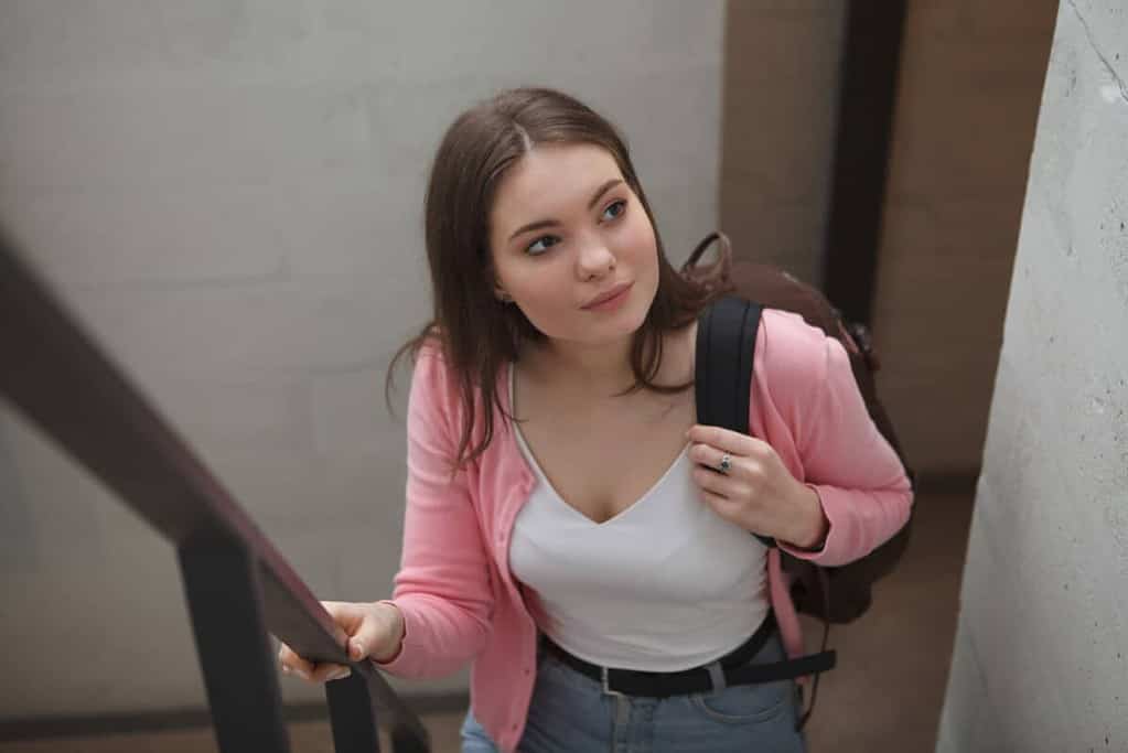 Female freelancer carrying backpack, walking up the stairs